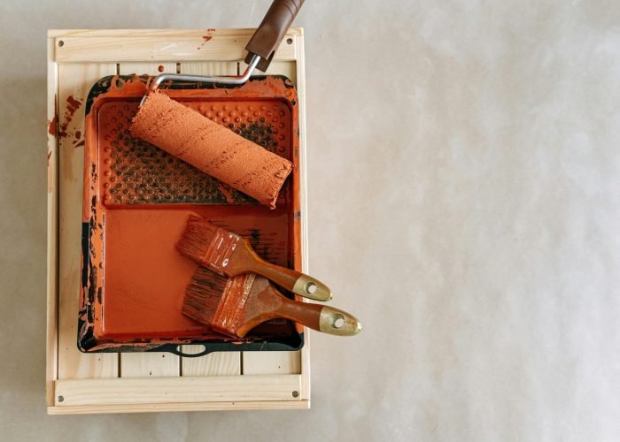 An overhead shot of paintbrushes and a roller in a tray, perfect for home renovation projects.