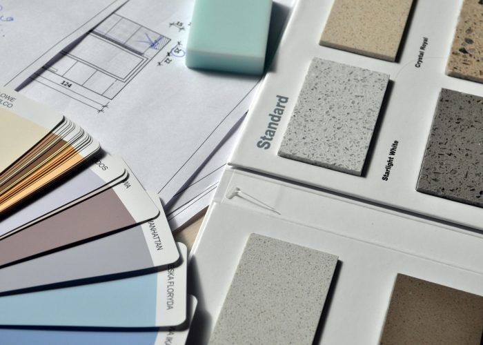 Color palette and material samples for interior renovation projects on a blueprint.